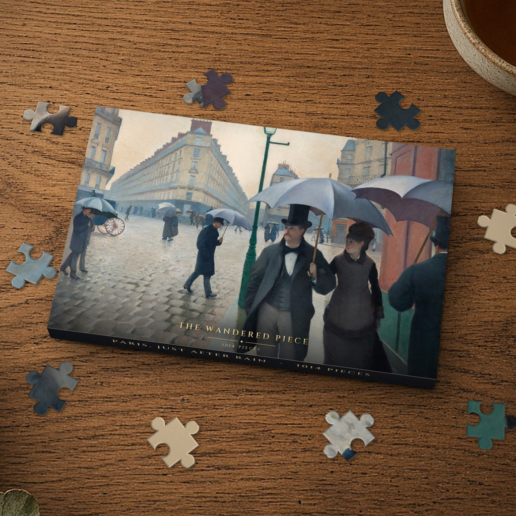 Paris, Just After Rain 1014 piece puzzle box on a wood table with loose pieces, box design shown for illustration