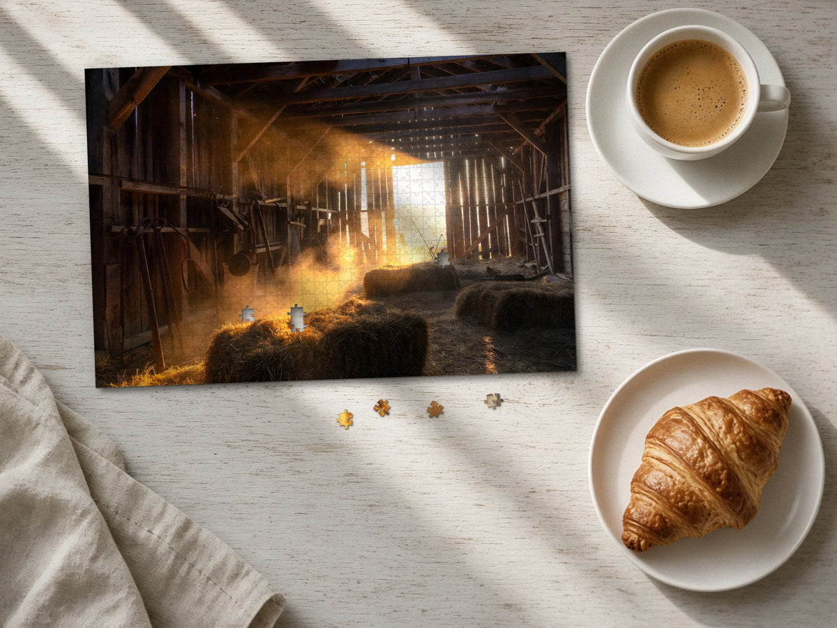 The Barn That Held the Day 1014 piece puzzle laid flat on a pale wood table in morning sun beside a cappuccino and a croissant