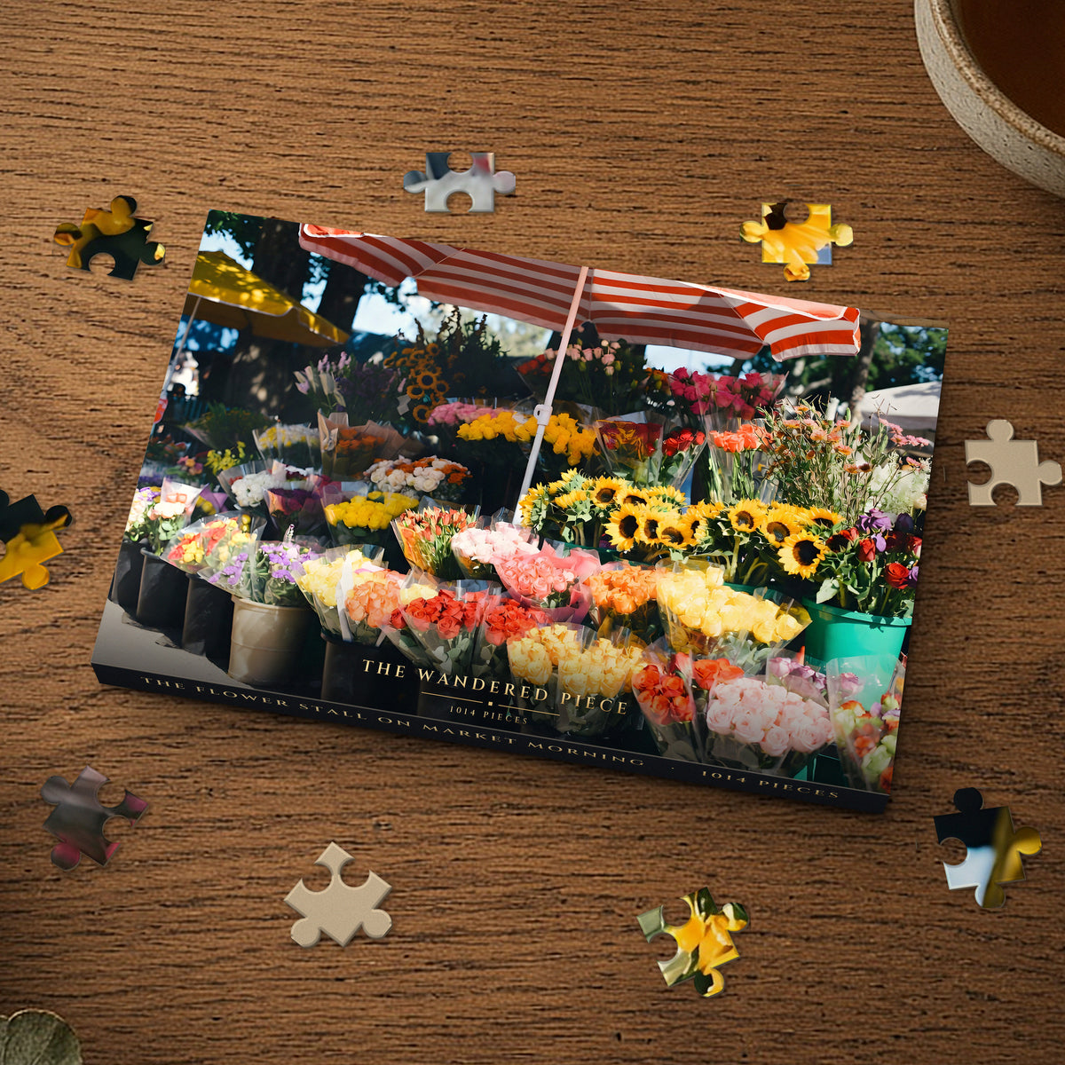 The Flower Stall on Market Morning 1014 piece puzzle box on a wood table with loose pieces, box design shown for illustration
