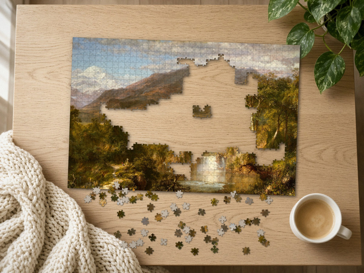 The Hidden Falls of the Andes 1014 piece puzzle half assembled on a light oak table, loose pieces scattered beside a chunky knit throw, a latte and a trailing plant