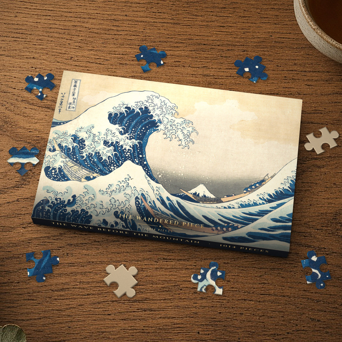 The Wave Before the Mountain 1014 piece puzzle box on a wood table with loose pieces, box design shown for illustration